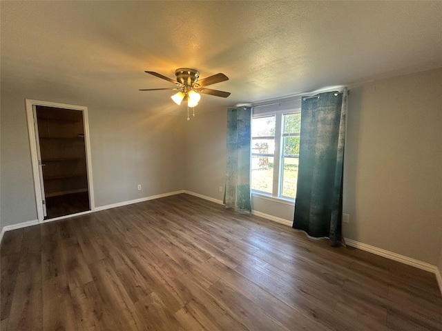 unfurnished room featuring dark wood finished floors, a textured ceiling, baseboards, and ceiling fan