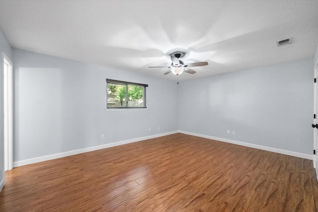 unfurnished room with wood finished floors, visible vents, a ceiling fan, and baseboards