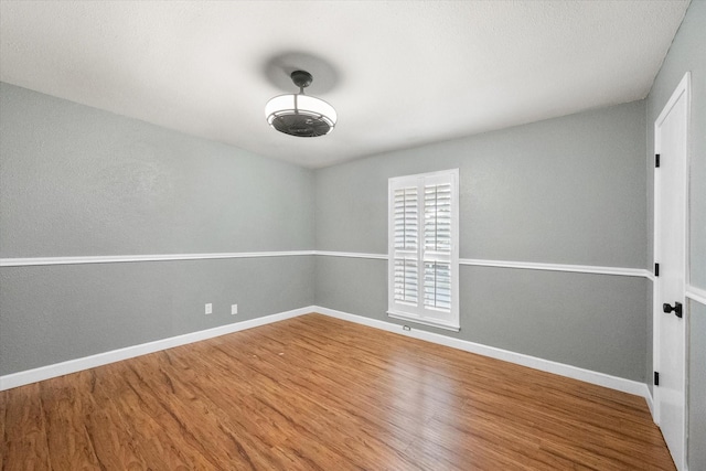 spare room with baseboards and wood finished floors
