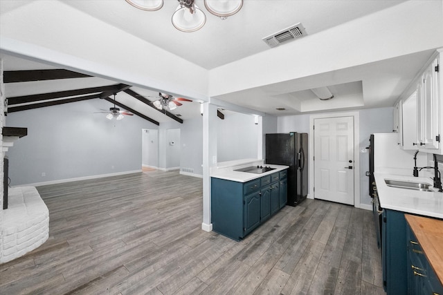 kitchen with a sink, blue cabinets, black appliances, light countertops, and visible vents