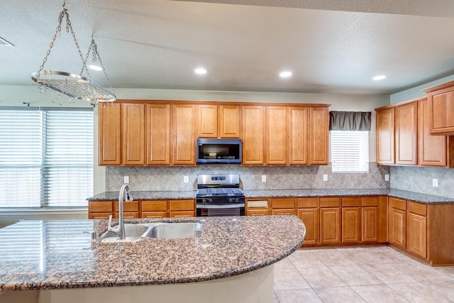 10625 Sexton Dr, Mckinney, TX 75072 - kitchen with stainless steel range with gas stovetop, dark stone counters, backsplash, brown cabinets, and recessed lighting