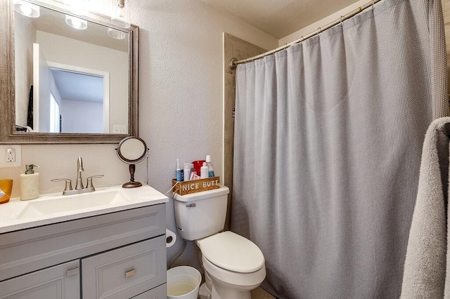 bathroom with toilet, a textured wall, vanity, and a shower with shower curtain