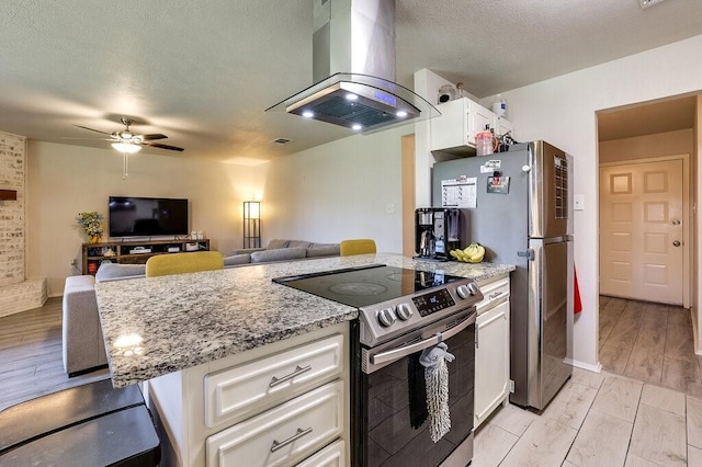 kitchen featuring stainless steel appliances, a ceiling fan, island exhaust hood, and light stone counters