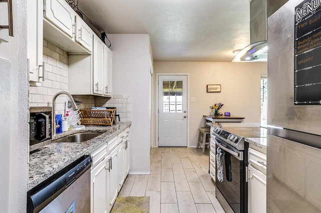 kitchen with white cabinets, a sink, backsplash, and appliances with stainless steel finishes