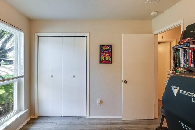 bedroom featuring baseboards, wood finished floors, and a closet