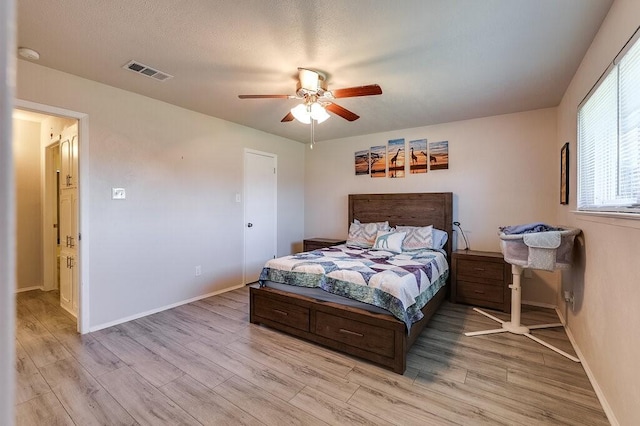 bedroom with light wood-style flooring, visible vents, and ceiling fan