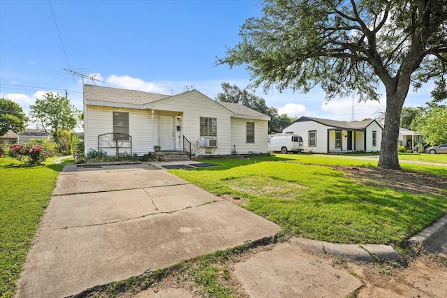bungalow featuring a shingled roof, a front yard, cooling unit, and concrete driveway