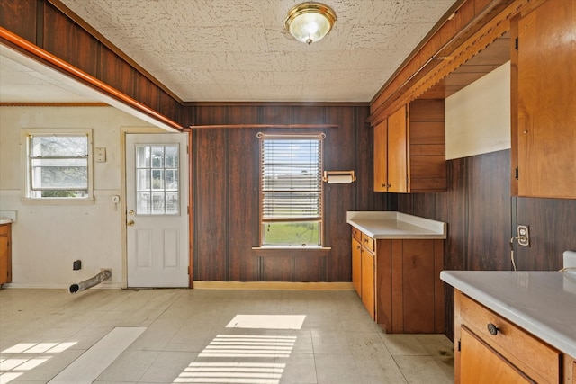 kitchen with brown cabinetry, wooden walls, and light countertops