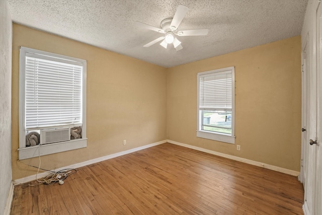 spare room with a textured ceiling, cooling unit, baseboards, a ceiling fan, and hardwood / wood-style floors