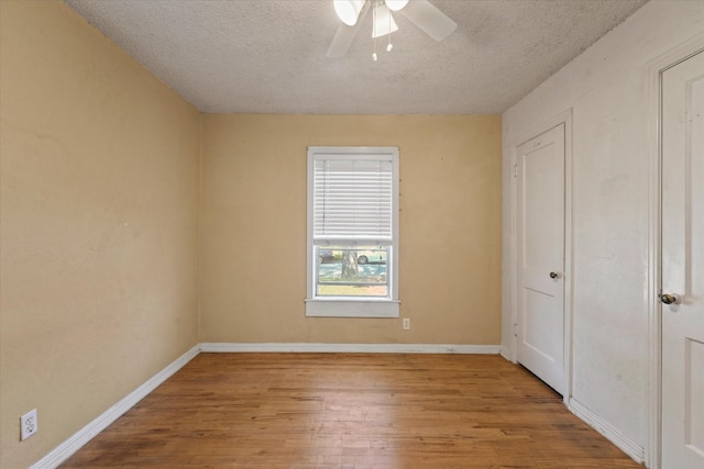 unfurnished bedroom featuring baseboards, wood finished floors, and a textured ceiling