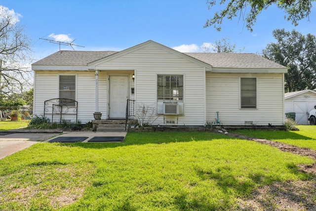 bungalow-style home featuring cooling unit, a shingled roof, and a front yard