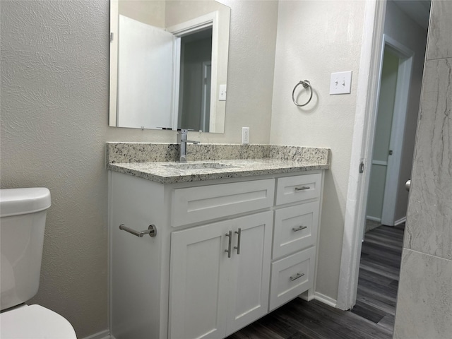 1928 Las Cruces Ln, Dallas, TX 75217 - bathroom featuring baseboards, wood finished floors, toilet, and vanity