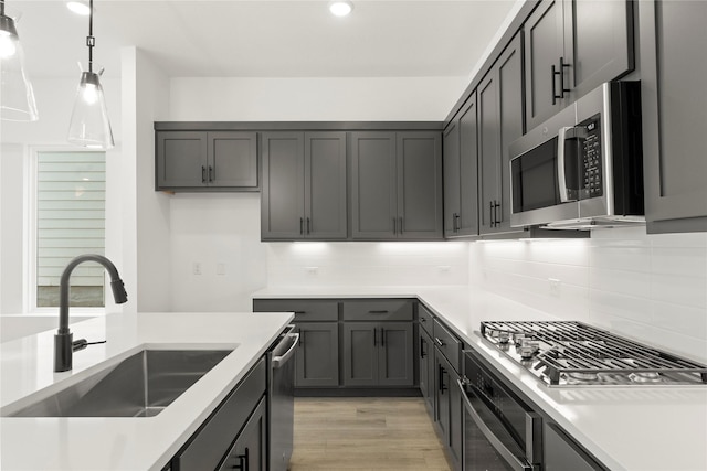 913 Janwood Dr, Plano, TX 75075 - kitchen with stainless steel appliances, a sink, decorative backsplash, decorative light fixtures, and light wood-style floors