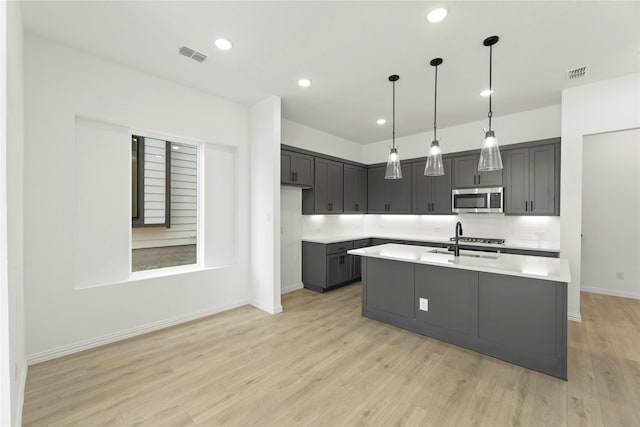 913 Janwood Dr, Plano, TX 75075 - kitchen with stainless steel appliances, light countertops, baseboards, light wood-style floors, and an island with sink