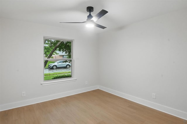 spare room featuring a ceiling fan, light wood-style flooring, and baseboards