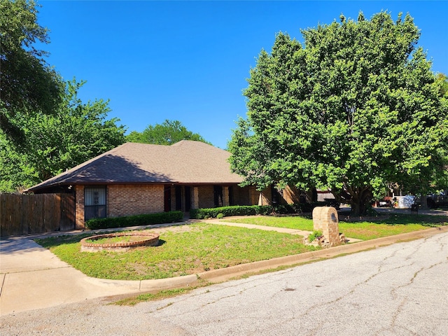 ranch-style house featuring fence, a front lawn, brick siding, and concrete driveway