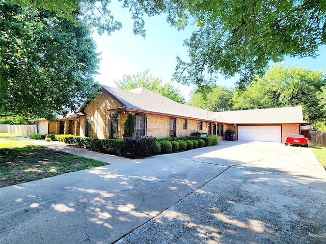 ranch-style home with brick siding, an attached garage, fence, and driveway