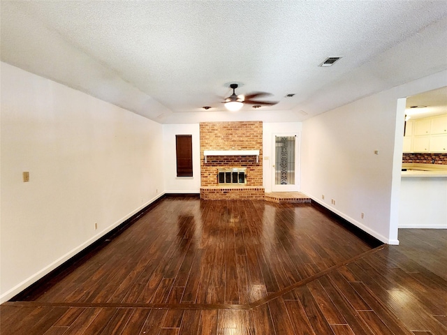 unfurnished living room with a textured ceiling, baseboards, ceiling fan, a fireplace, and wood-type flooring