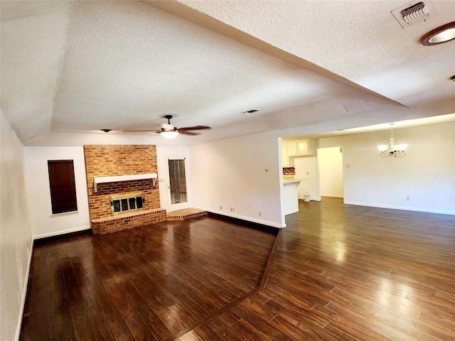 unfurnished living room featuring a fireplace, ceiling fan with notable chandelier, a textured ceiling, and visible vents
