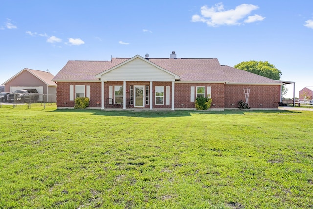 rear view of property featuring brick siding, a yard, and fence