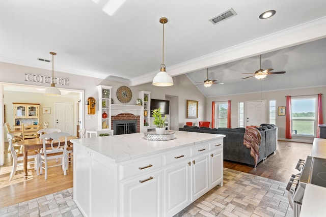kitchen with a center island, electric range, white cabinets, ornamental molding, and visible vents