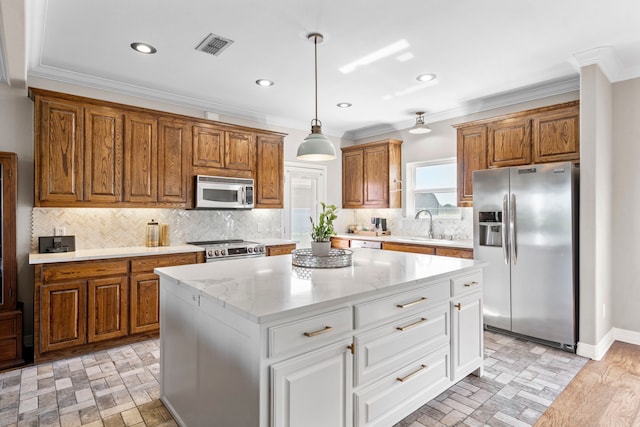 kitchen with brown cabinetry, appliances with stainless steel finishes, ornamental molding, visible vents, and a kitchen island