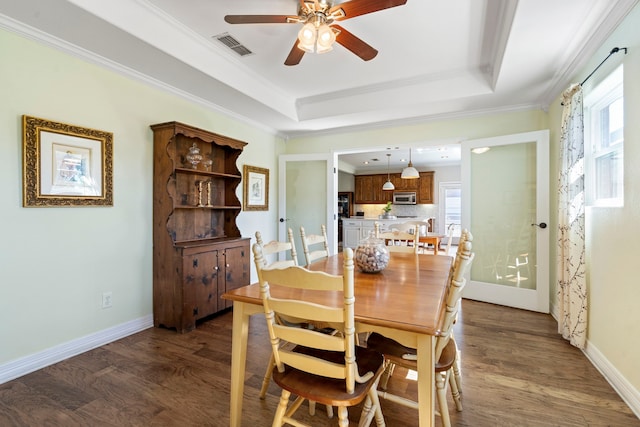 dining area with a tray ceiling, wood finished floors, a healthy amount of sunlight, a ceiling fan, and crown molding