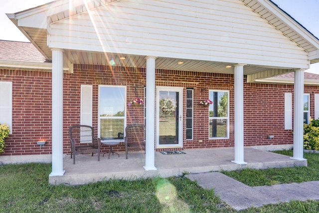 doorway to property with brick siding and a patio