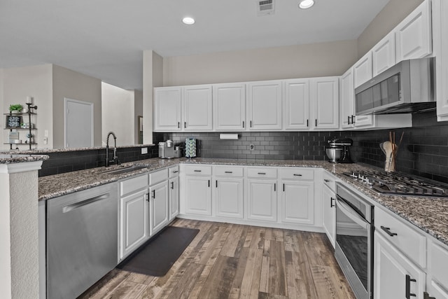 9112 Manassas Rdg, Mckinney, TX 75071 - kitchen with stainless steel appliances, a sink, light wood-type flooring, white cabinets, and backsplash
