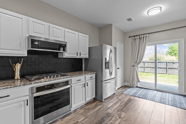 9112 Manassas Rdg, Mckinney, TX 75071 - kitchen with stainless steel appliances, wood finished floors, dark stone countertops, and backsplash