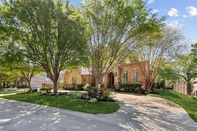 view of front of home featuring fence, a front yard, brick siding, and curved driveway