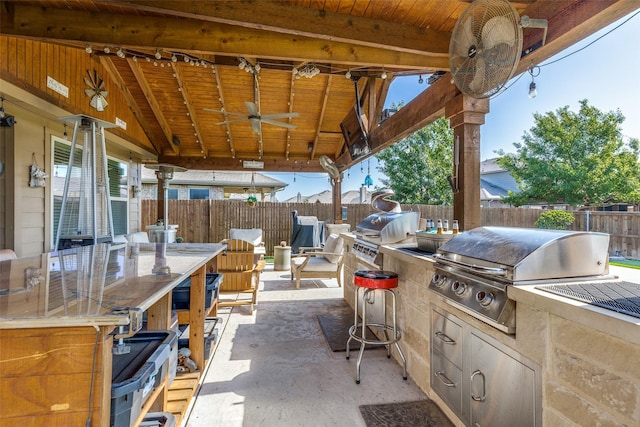 view of patio featuring a fenced backyard, a ceiling fan, exterior kitchen, and a grill