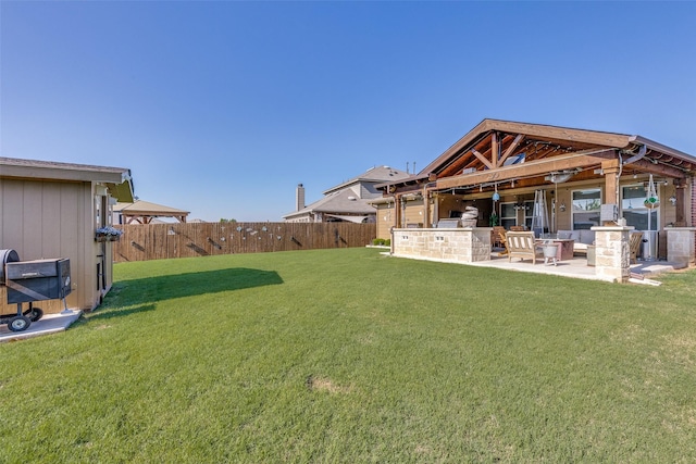 view of yard featuring a gazebo, an outdoor kitchen, a fenced backyard, and a patio