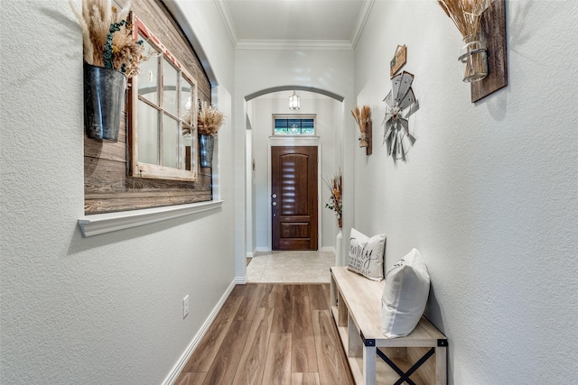 entryway featuring arched walkways, baseboards, wood finished floors, crown molding, and a textured wall
