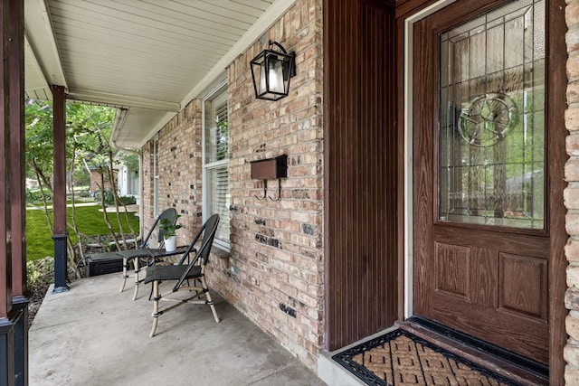 entrance to property with brick siding and covered porch