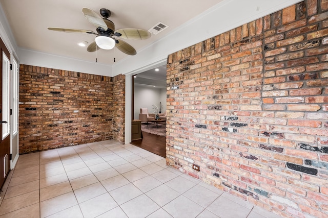 spare room with visible vents, a ceiling fan, brick wall, and light tile patterned floors