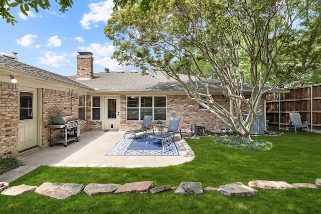 rear view of property featuring brick siding, a lawn, a chimney, and fence