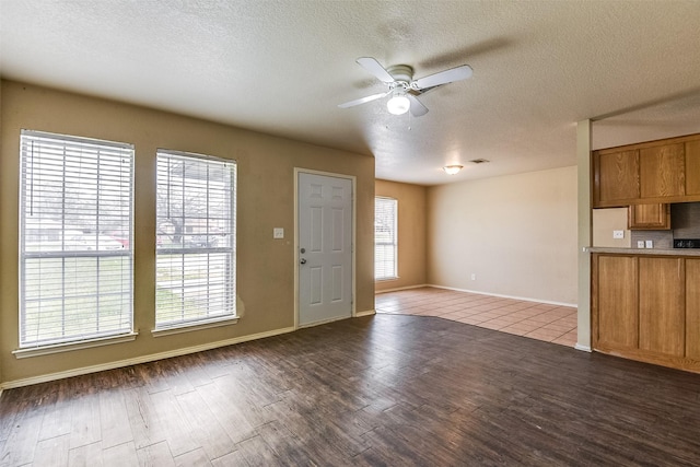2545 E Renfro St, Burleson, TX 76028 - unfurnished living room with dark wood finished floors, a textured ceiling, a ceiling fan, and baseboards