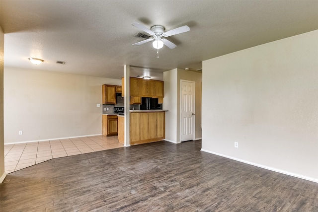 2545 E Renfro St, Burleson, TX 76028 - unfurnished living room with wood finished floors, visible vents, baseboards, a textured ceiling, and ceiling fan
