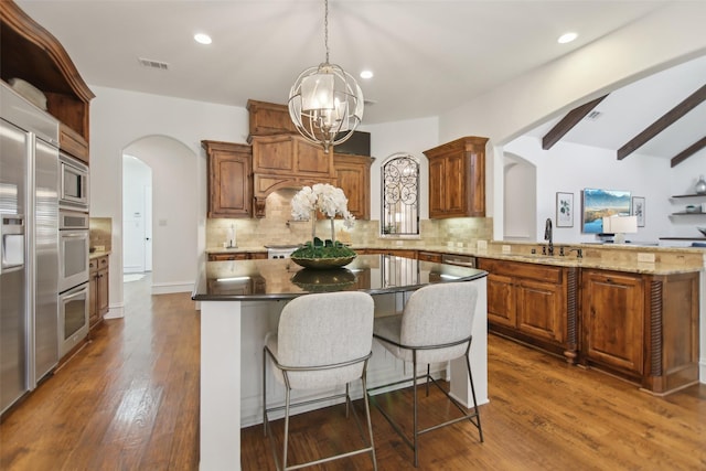 kitchen featuring tasteful backsplash, a sink, visible vents, arched walkways, and a notable chandelier