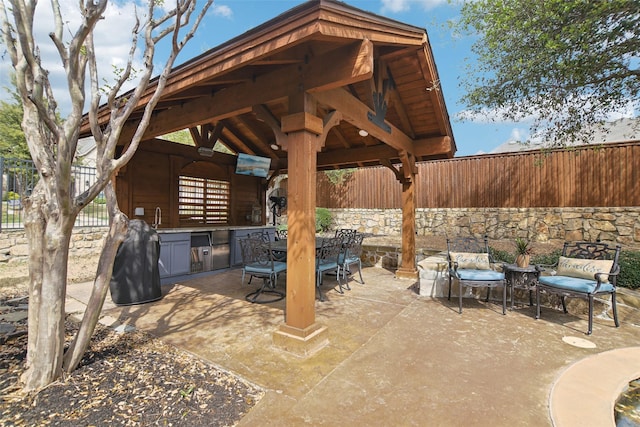 view of patio / terrace with a gazebo, a sink, outdoor dining area, and a fenced backyard