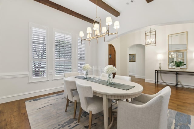 dining area featuring wood finished floors, arched walkways, beamed ceiling, baseboards, and a notable chandelier