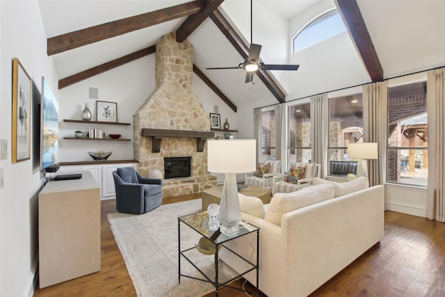 living area featuring a stone fireplace, wood finished floors, beam ceiling, and ceiling fan