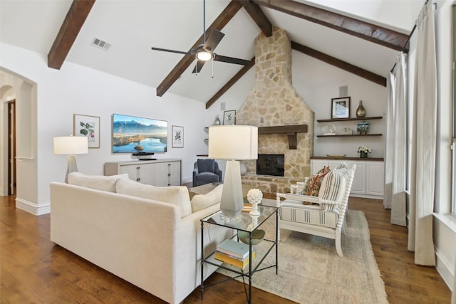 living room featuring a ceiling fan, a stone fireplace, dark wood finished floors, baseboards, and visible vents