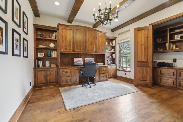 office space featuring beam ceiling, baseboards, a chandelier, wood finished floors, and built in study area