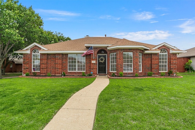 ranch-style home featuring brick siding, roof with shingles, and a front yard