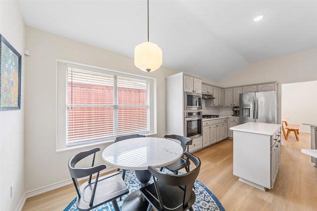 kitchen with stainless steel appliances, a center island, light wood-style floors, lofted ceiling, and light countertops