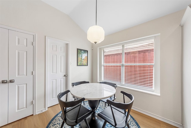 dining space featuring vaulted ceiling, light wood finished floors, and baseboards