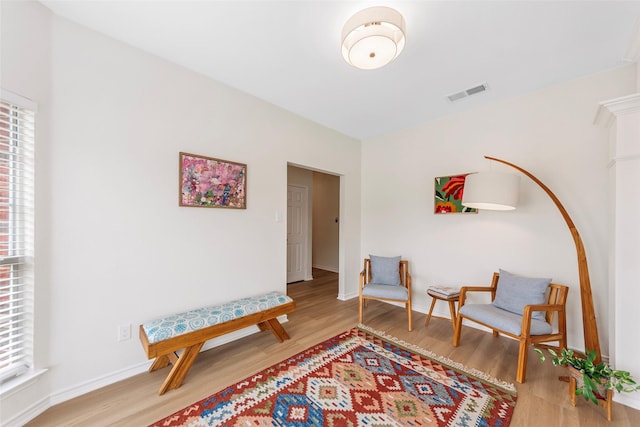 sitting room featuring light wood-type flooring, visible vents, and baseboards