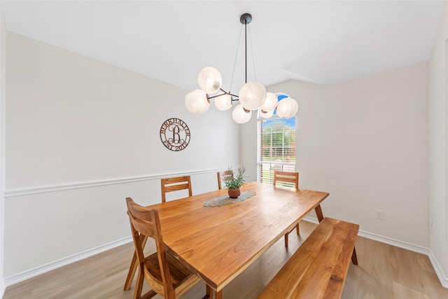 dining room with lofted ceiling, light wood-style flooring, baseboards, and a chandelier